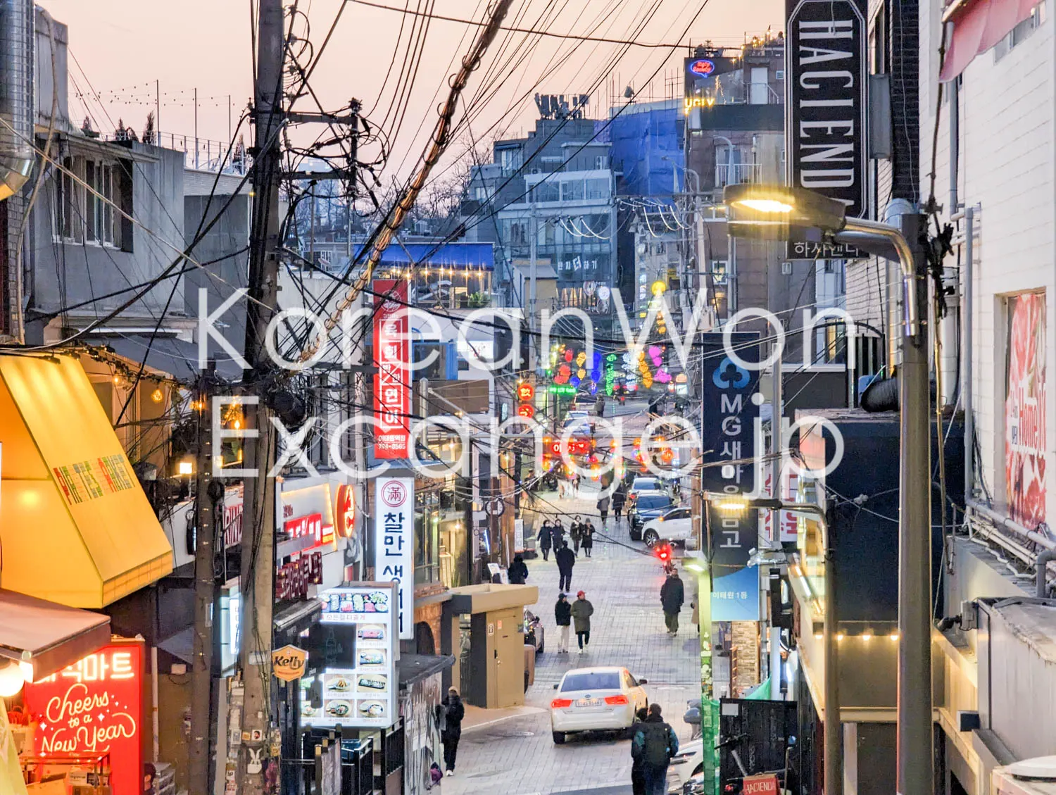 A narrow Seoul alley at dusk, packed with signs and tangled overhead wires.